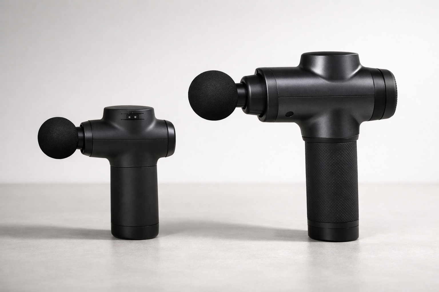 Twee massage guns naast elkaar: compact model en full-size model.